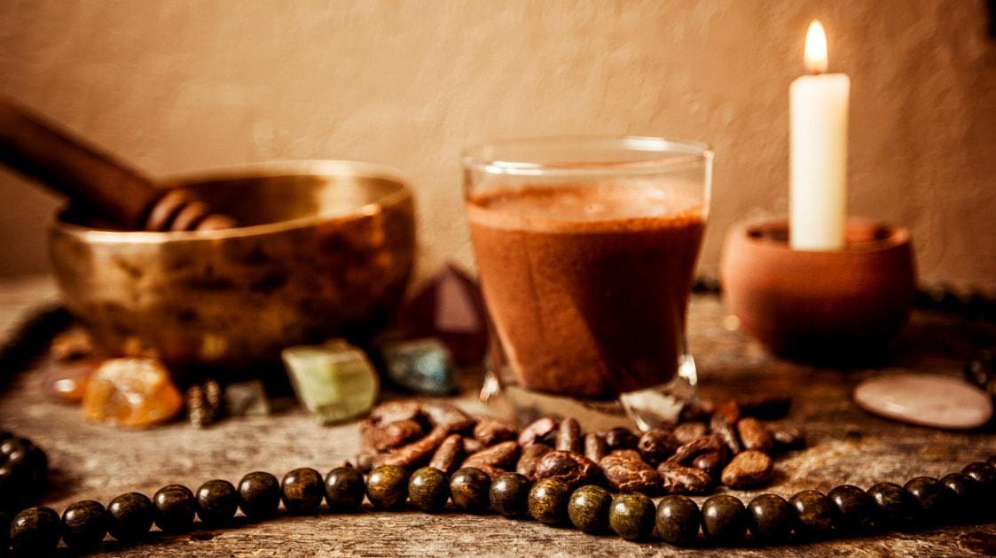 Coffee, a singing bowl, a single white candle, and crystals sitting on stone