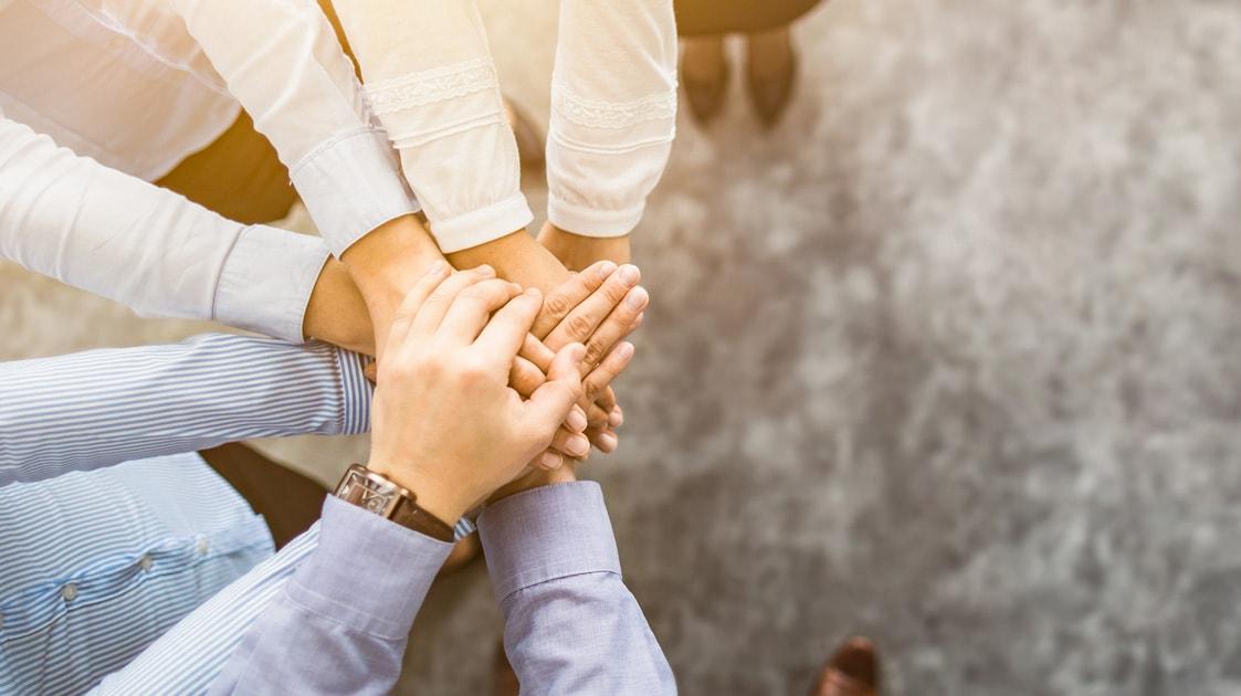 Group of business people with their hands stacked on top of each other, from the top down